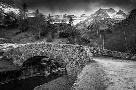 Sunset over the Pyrenees mountains, Circus of Gavarnie and the old stone bridge spanning the stream, High quality photo