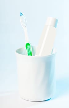 Toothbrushes in glass on table on light background