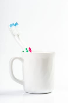 Toothbrushes in glass on table on light background