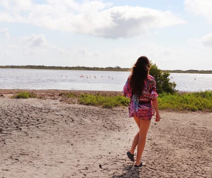 Woman walking toward the lake with flamingos