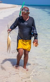 03.03.2024 - Cayo Coco Island, Cuba - Local diver with caught octopus and seashells