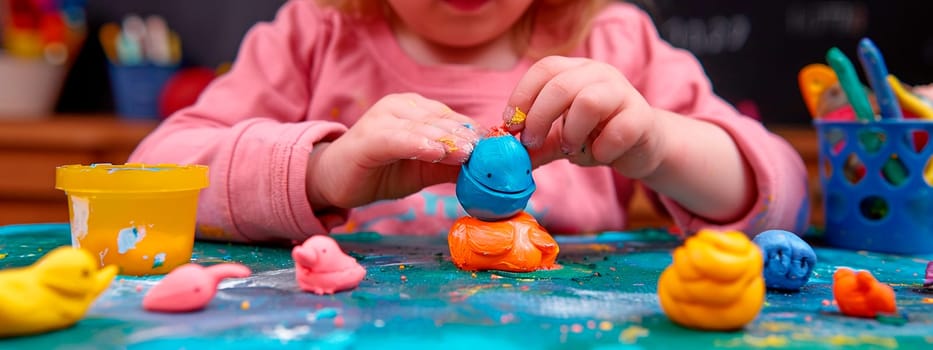 child sculpting plasticine on the table. selective focus. people.
