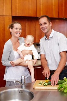 Portrait, family and people in kitchen for love, happiness and bonding at home, house and apartment together. Man, woman and baby with vegetables for salad, nutrition and wellness with smile or laugh.