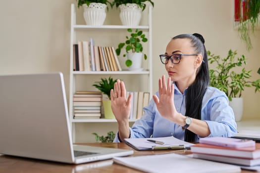 Woman psychologist mental therapist counselor social worker work remotely using computer for online therapy session. Female with clipboard looking at laptop, showing psychological gestures to patient