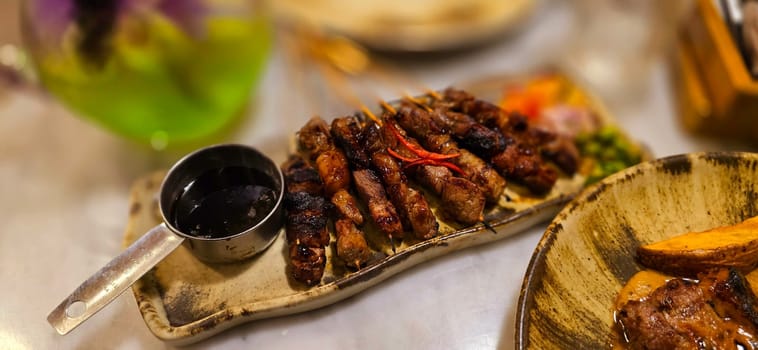 Homemade beef Satay marinated with spice and sweet soy sauce, coriander beef satay, served on plate with onion, chilli, soy sauce and tomato. Indonesian traditional food