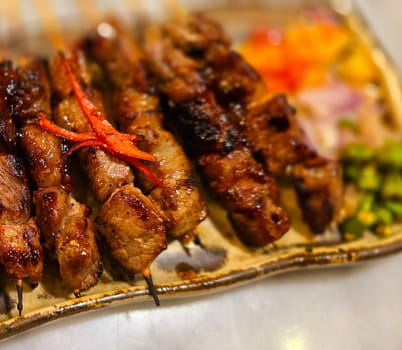 Homemade beef Satay marinated with spice and sweet soy sauce, coriander beef satay, served on plate with onion, chilli, soy sauce and tomato. Indonesian traditional food