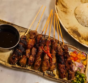 Homemade beef Satay marinated with spice and sweet soy sauce, coriander beef satay, served on plate with onion, chilli, soy sauce and tomato. Indonesian traditional food