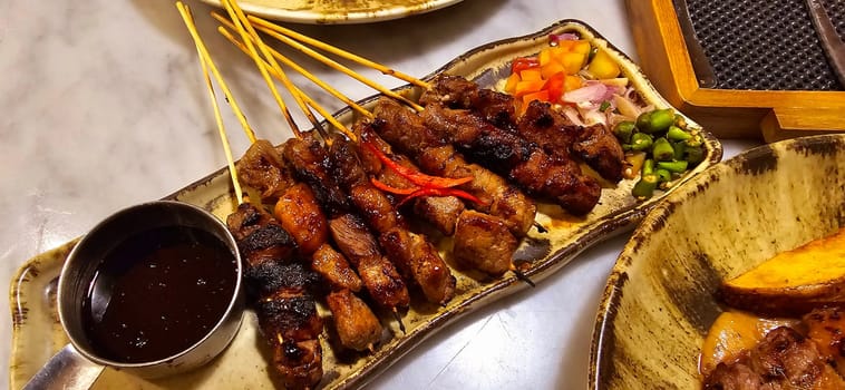 Homemade beef Satay marinated with spice and sweet soy sauce, coriander beef satay, served on plate with onion, chilli, soy sauce and tomato. Indonesian traditional food