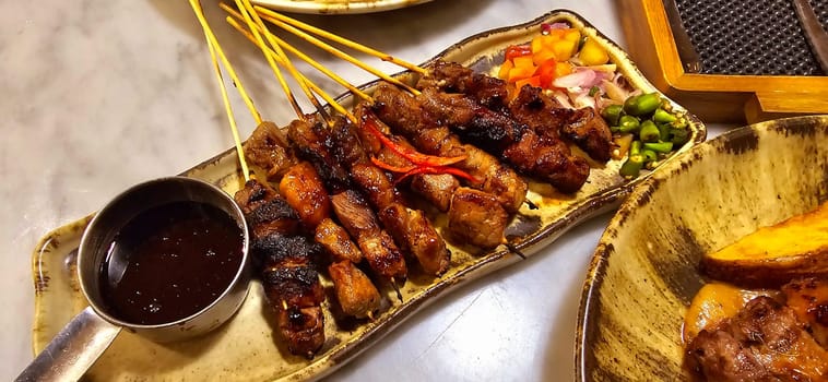 Homemade beef Satay marinated with spice and sweet soy sauce, coriander beef satay, served on plate with onion, chilli, soy sauce and tomato. Indonesian traditional food