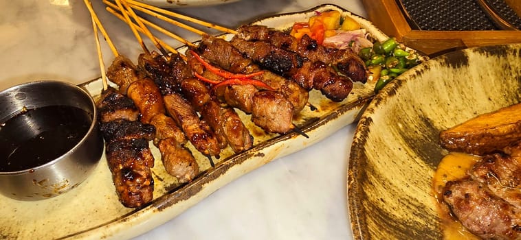 Homemade beef Satay marinated with spice and sweet soy sauce, coriander beef satay, served on plate with onion, chilli, soy sauce and tomato. Indonesian traditional food