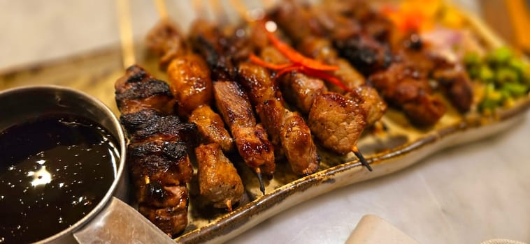 Homemade beef Satay marinated with spice and sweet soy sauce, coriander beef satay, served on plate with onion, chilli, soy sauce and tomato. Indonesian traditional food