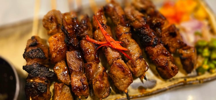 Homemade beef Satay marinated with spice and sweet soy sauce, coriander beef satay, served on plate with onion, chilli, soy sauce and tomato. Indonesian traditional food