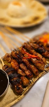 Homemade beef Satay marinated with spice and sweet soy sauce, coriander beef satay, served on plate with onion, chilli, soy sauce and tomato. Indonesian traditional food