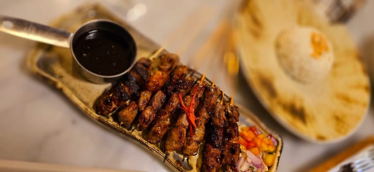 Homemade beef Satay marinated with spice and sweet soy sauce, coriander beef satay, served on plate with onion, chilli, soy sauce and tomato. Indonesian traditional food