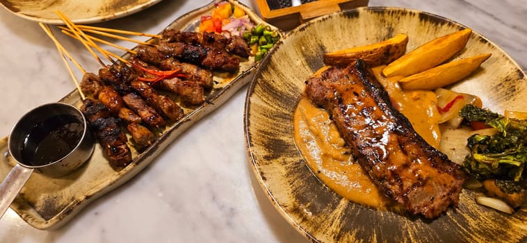 Homemade beef Satay marinated with spice and sweet soy sauce, coriander beef satay, served on plate with onion, chilli, soy sauce and tomato. Indonesian traditional food