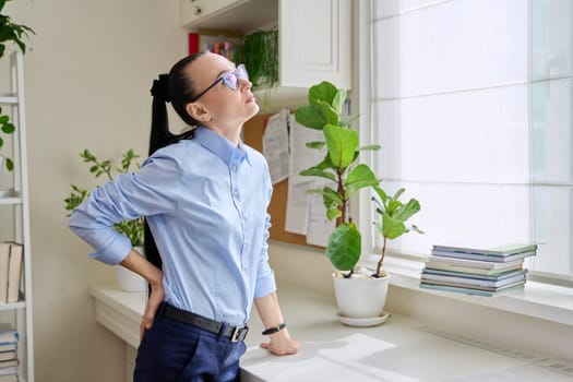 Woman having back pain, female holding her lower back with her hand. Health, back diseases, people concept