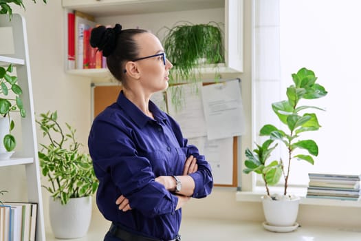 Serious thoughtful confident woman with crossed arms looking out the window. Emotions, lifestyle, health, people concept