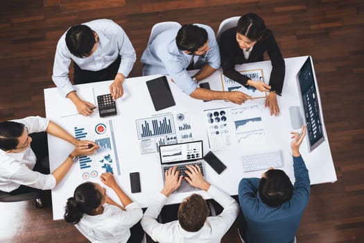 Top view analyst team utilizing BI Fintech to analyze financial data at table in meeting room. Analytic BI dashboard power on paper for business insight and strategic marketing planning. Prudent