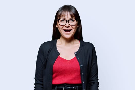 Surprised joyful middle-aged woman on gray studio background. Happy 40s female looking at camera with open mouth. Lifestyle, work, beauty, expertise, health, mature people concept