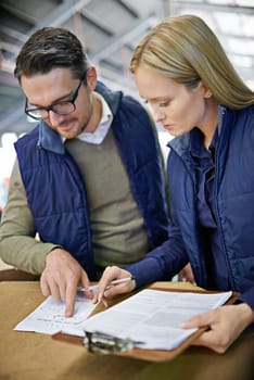 Business people, reading and checklist with inventory, storage or supply chain at warehouse. Coworkers, team or employees looking at documents, paperwork or clipboard for distribution at factory.