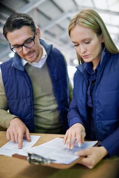 Business people, reading and planning with checklist for inventory, storage or supply chain at warehouse. Happy coworkers, team or employees looking at documents, paperwork or distribution at factory.