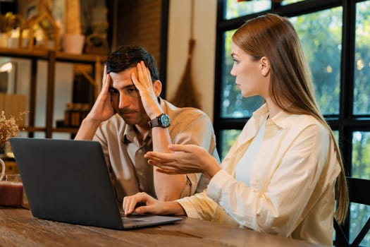 Young couple working remotely on laptop in cafe look tired and frustrated. Digital nomad freelancers or college students struggling to meet a deadline overwhelmed by workload. Expedient