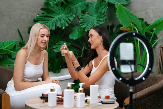 Two beautiful content creator making natural beauty and cosmetic tutorial on green plant garden video. Beauty blogger showing how to beauty care to social medial audience using selfie stick . Blithe