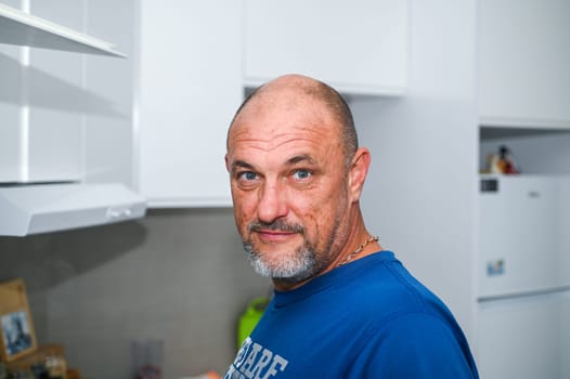 man with gray eyes in a blue T-shirt in a white kitchen 1