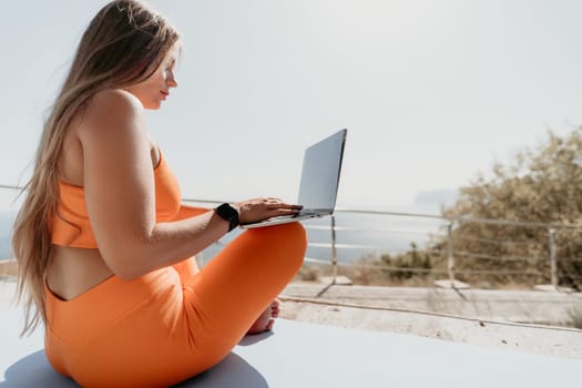 Digital nomad, Business woman working on laptop by the sea. Pretty lady typing on computer by the sea at sunset, makes a business transaction online from a distance. Freelance, remote work on vacation