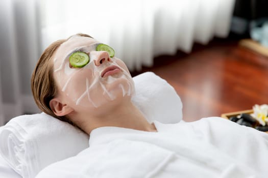 Serene daylight ambiance of spa salon, woman customer indulges in rejuvenating with luxurious cucumber facial mask. Facial skincare treatment and beauty care concept. Quiescent