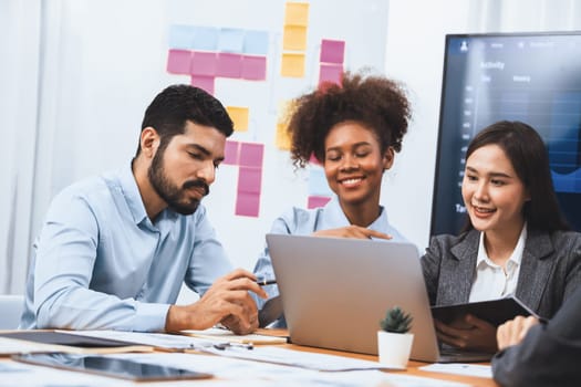 Multiracial analyst team use BI dashboard data to analyze financial report on meeting table. Group of diverse business people utilize data analysis by FIntech for success business marketing. Concord