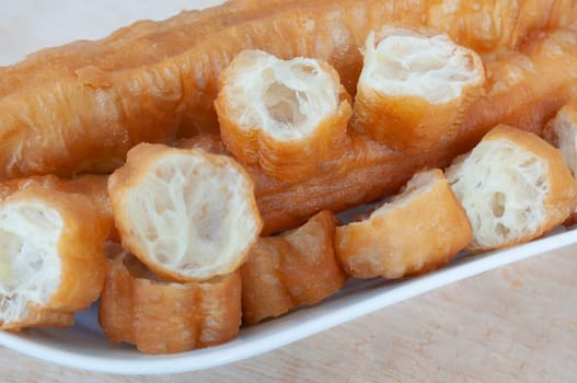 Close up of cut cakoi or youtiao cake on white plate. Asian food concept.