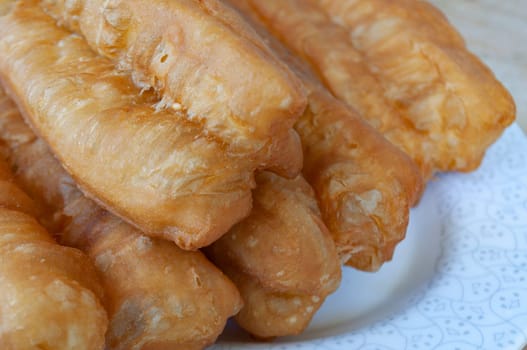 Close up of cakoi or Youtiao on white plate with customizable space for text. Asian food concept.