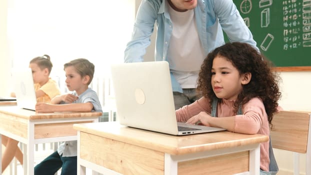 American girl learning about coding engineering prompt while diverse students sitting at STEM technology class. Multicultural children working on laptop to generated AI by using software. Pedagogy.