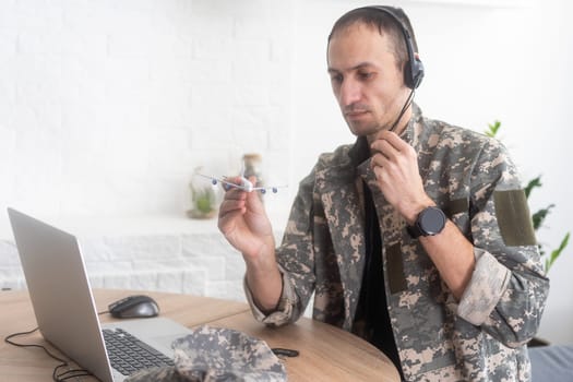 Military Technical Service, Air Force Concept. Hands of a man in uniform holding a silver toy airplane. A middle-aged adult man in a green camouflage uniform. Indoors. High quality photo