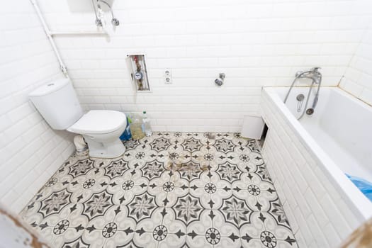 Interior of narrow restroom with wall hung toilet with white walls and checkered floor. High quality photo