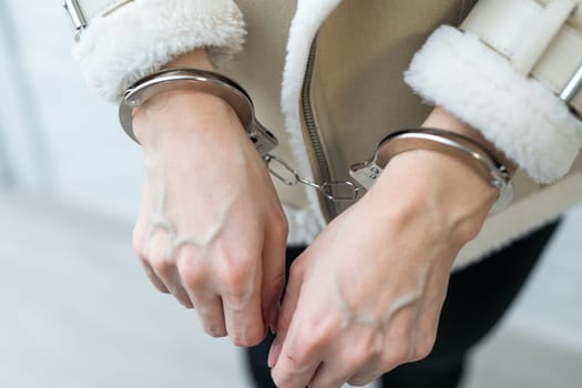 A woman who has been arrested and has her hands handcuffed behind her back to the rear. The prisoner is awaiting transport to the jail. High quality photo