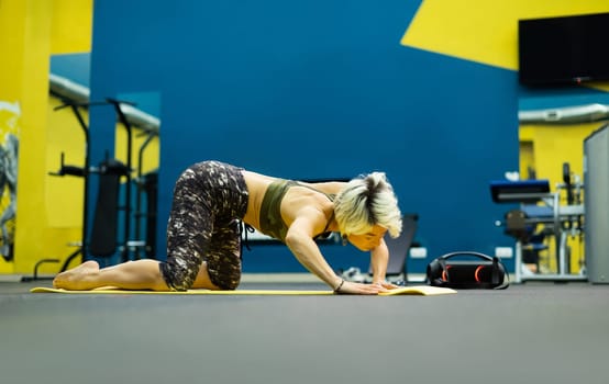 slender athletic woman in the gym is beautifully engaged in yoga exercises on a mat