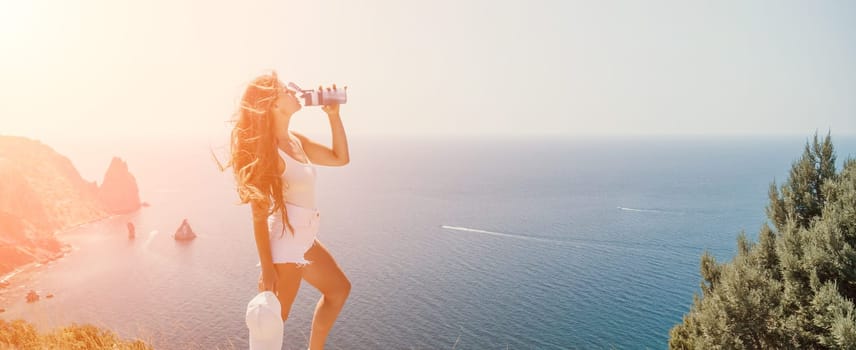 Woman travel sea. Young Happy woman in a long red dress posing on a beach near the sea on background of volcanic rocks, like in Iceland, sharing travel adventure journey