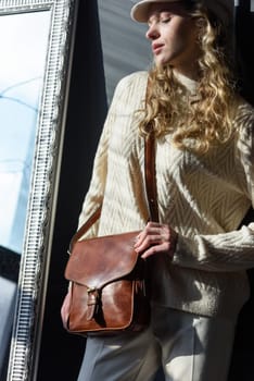 beautiful curly blond hair woman posing with a small brown Model wearing stylish cap white sweater and classic trousers