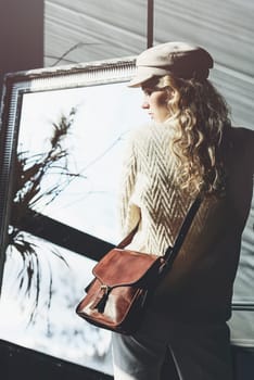 beautiful curly blond hair woman posing with a small brown Model wearing stylish cap white sweater and classic trousers