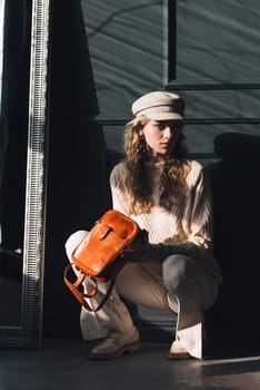 beautiful curly blond hair woman posing squatting with a small brown Model wearing stylish cap white sweater and classic trousers