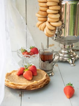 Still life in the Russian tradition for Maslenitsa, pancakes with honey and strawberries, tea from a samovar with bagels, Slavic holiday, High quality photo