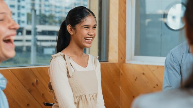 Young student smiling while listening other student in meeting or group discussion. Cute teenager talking about her experience and sharing to friends in mixed races. Creative education. Edification.