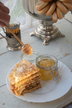 Russian pancakes with honey and a cup of tea from a vintage samovar Maslenitsa festival concept, High quality photo