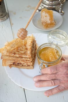 A man pours honey on pancakes and drinks tea from a samovar, Russian tradition of celebrating Maslenitsa. High quality photo