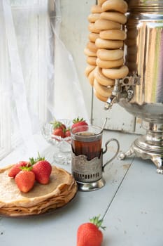 Still life in the Russian tradition for Maslenitsa, pancakes with honey and strawberries, tea from a samovar with bagels, Slavic holiday, High quality photo