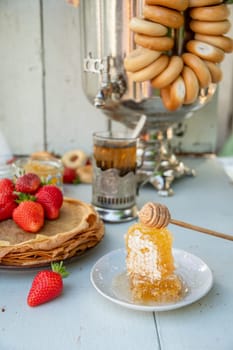 Still life in the Russian tradition for Maslenitsa, pancakes with honey and strawberries, tea from a samovar with bagels, Slavic holiday, High quality photo