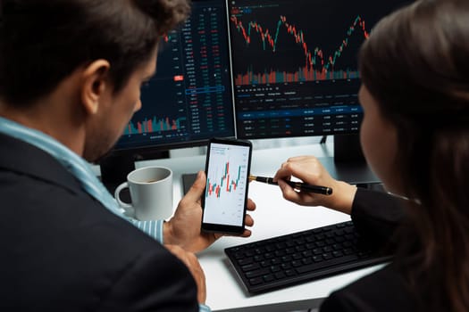 Focusing on phone with discussing dynamic stock market in two business traders online website compare with pc screens in real time currency rate investment on risk data at modern office. Postulate.