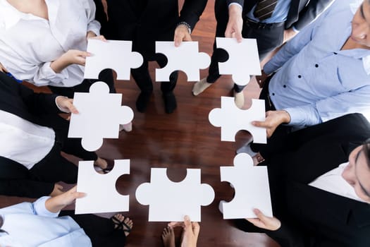 Top view multiethnic business people holding jigsaw pieces and merge them together as effective solution solving teamwork, shared vision and common goal combining diverse talent. Meticulous